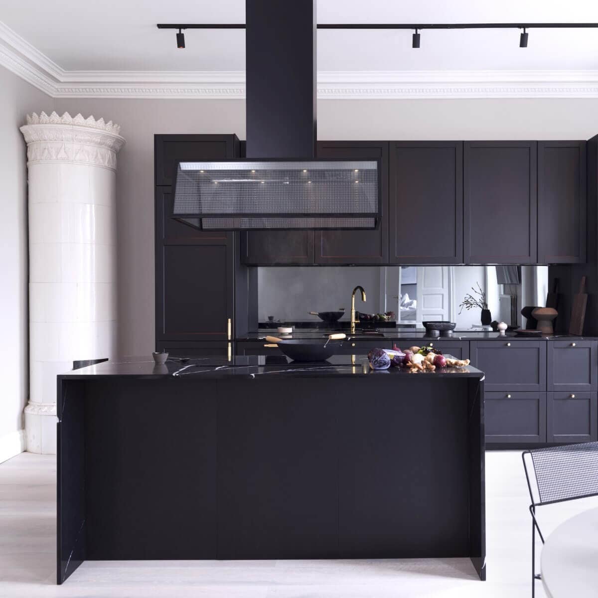 Frihängande köksfläkten Prisma i svart utförande ovanför köksö i modern sekelskiftesmiljö med mörka köksluckor.