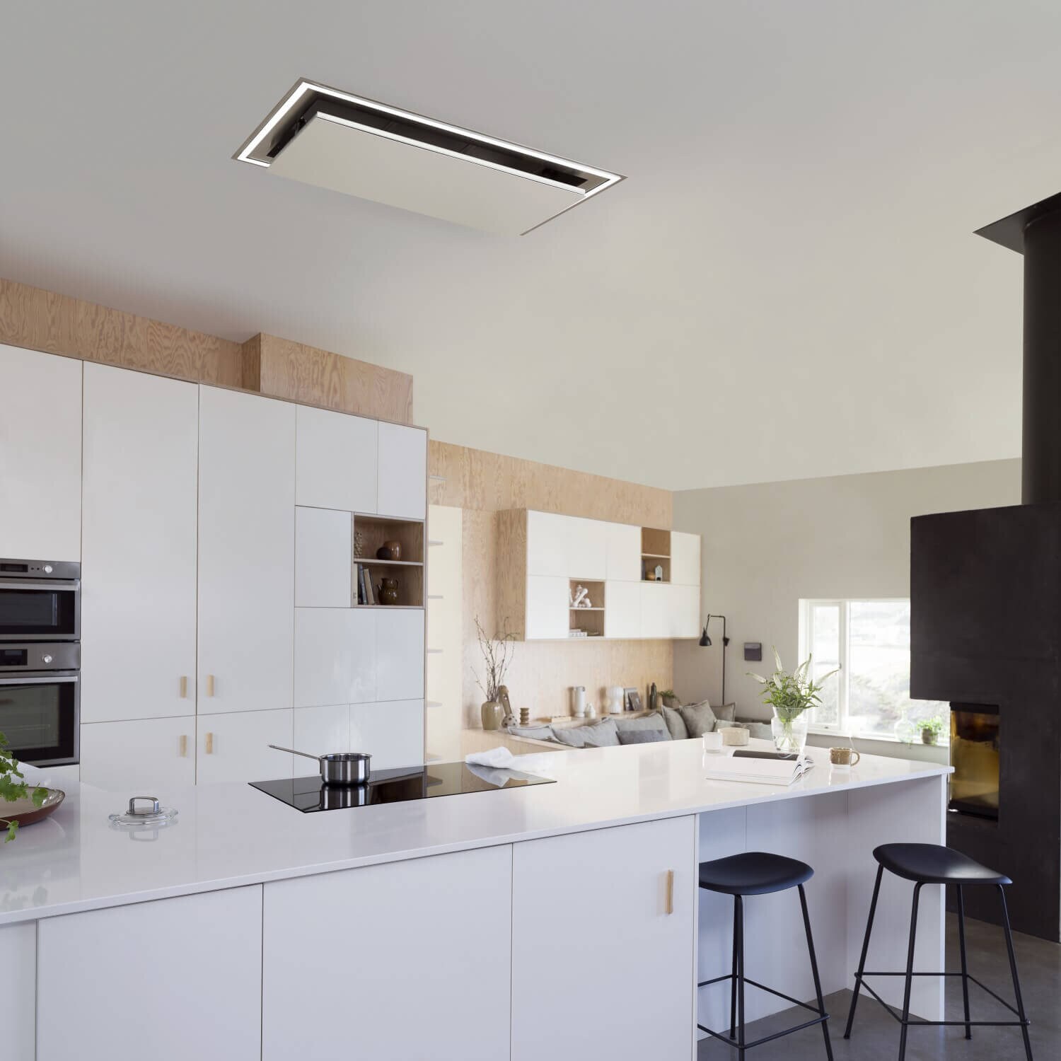 Takintegrerade köksfläkten Atrium i helvitt utförande med nedfälld lucka i ett ljust minimalistiskt kök.